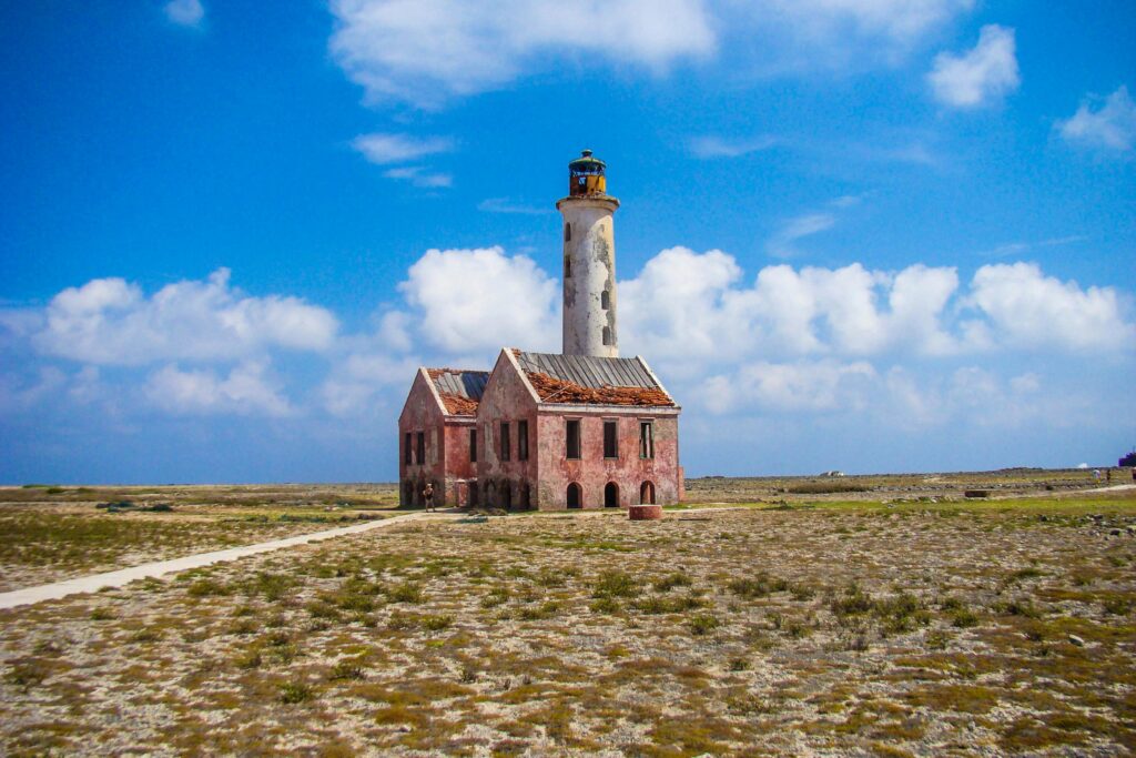 Aerial view of Klein Curaçao's iconic abandoned lighthouse under a vibrant, blue sky.