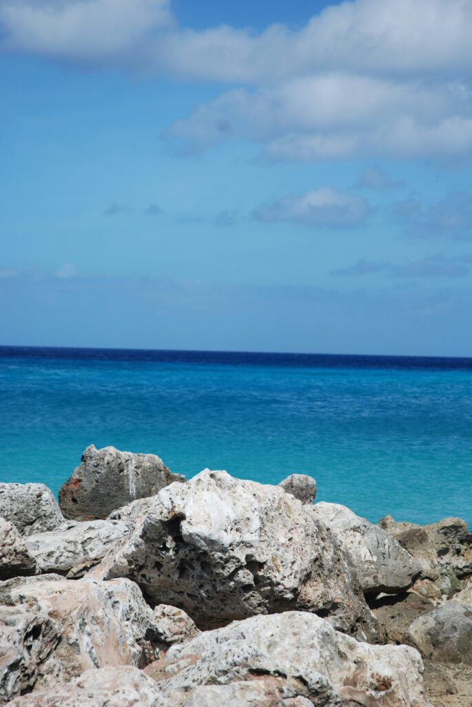 Picturesque rocky shoreline with stunning blue sea and sky in Curaçao, ideal for travel inspiration.